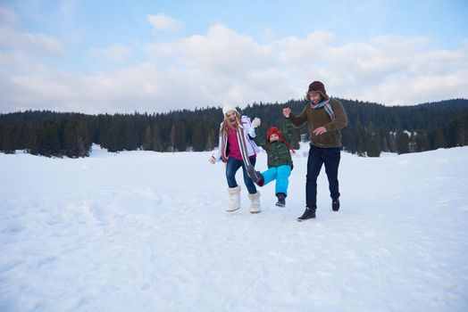 happy young  family playing in fresh snow  at beautiful sunny winter day outdoor in nature