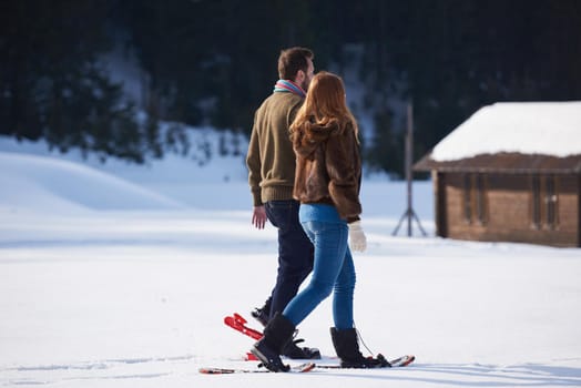 happy young  couple having fun and walking in snow shoes. Romantic winter relaxation scene