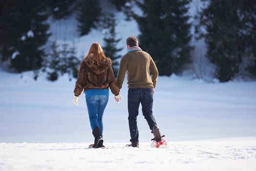 happy young  couple having fun and walking in snow shoes. Romantic winter relaxation scene