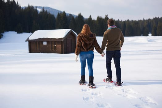 happy young  couple having fun and walking in snow shoes. Romantic winter relaxation scene