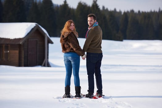 happy young  couple having fun and walking in snow shoes. Romantic winter relaxation scene