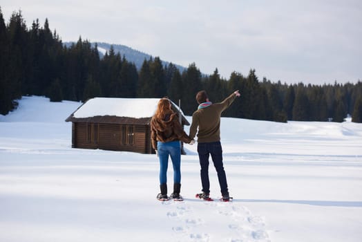 happy young  couple having fun and walking in snow shoes. Romantic winter relaxation scene