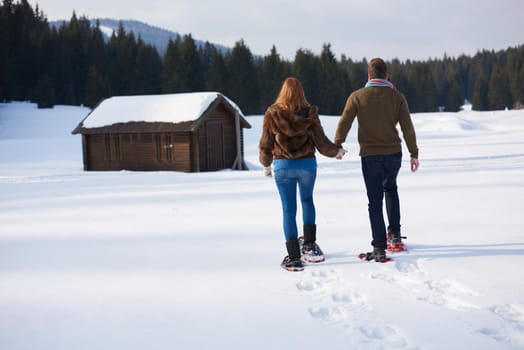 happy young  couple having fun and walking in snow shoes. Romantic winter relaxation scene