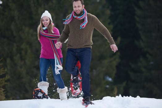 happy young  couple having fun and walking in snow shoes. Romantic winter relaxation scene