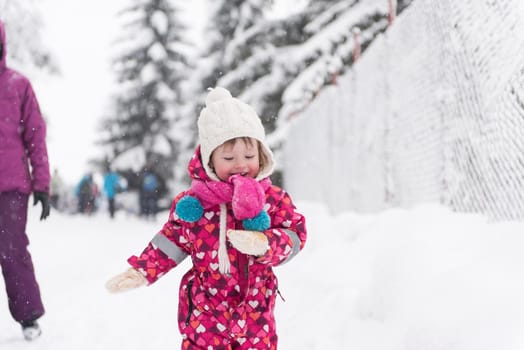 portrait of happy smiling little girl child outdoors having fun and playing on snowy winter day