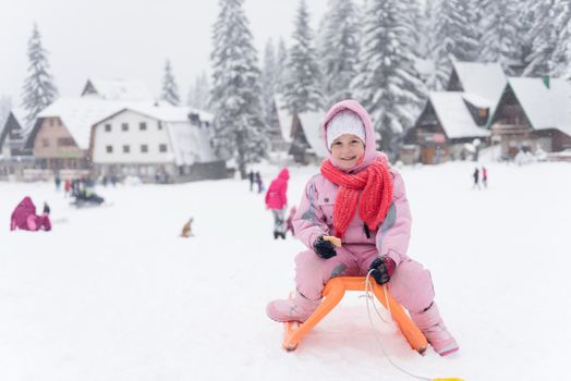 portrait of cute little girl child sitting on sledges at winter day with fresh snow,  eat cookies and have break