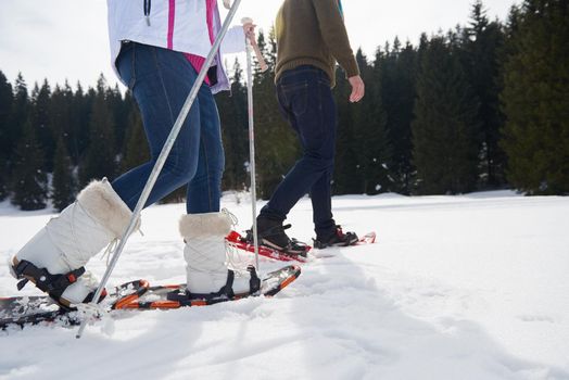 happy young  couple having fun and walking in snow shoes outdoor in nature at beautiful winter day. Health sport and relaxation