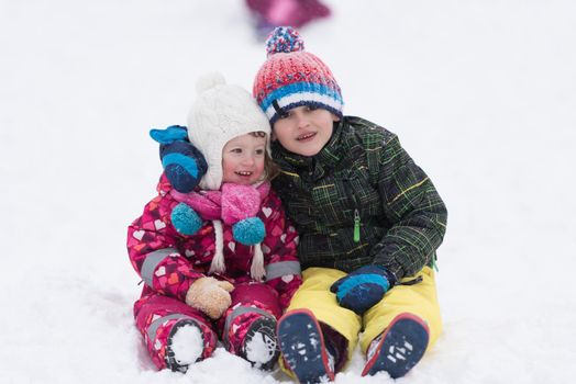 group of kids having fun and play together in fresh snow on winter vacation