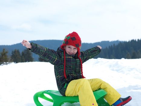 happy young boy have fun on winter vacatioin, sledding children on fresh snow at sunny day outdoor in nature