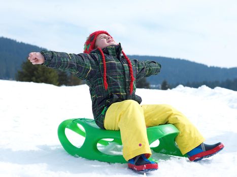 happy young boy have fun on winter vacatioin, sledding children on fresh snow at sunny day outdoor in nature