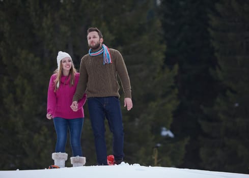 happy young  couple having fun and walking in snow shoes outdoor in nature at beautiful winter day. Health sport and relaxation