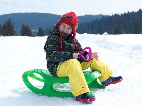 happy young boy have fun on winter vacatioin, sledding children on fresh snow at sunny day outdoor in nature