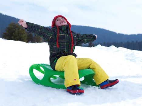 happy young boy have fun on winter vacatioin, sledding children on fresh snow at sunny day outdoor in nature