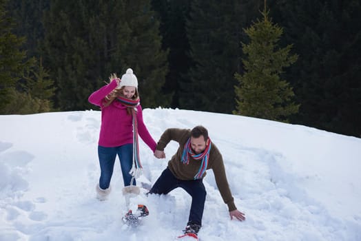 happy young  couple having fun and walking in snow shoes. Romantic winter relaxation scene