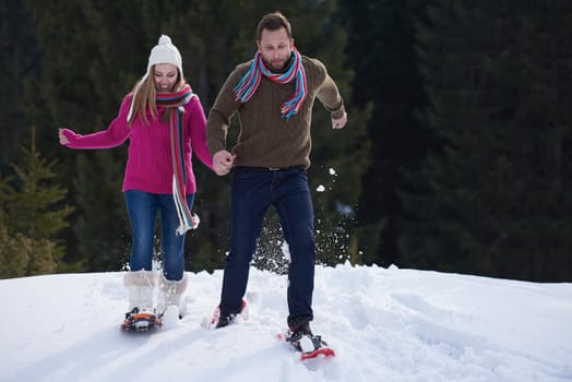 happy young  couple having fun and walking in snow shoes. Romantic winter relaxation scene