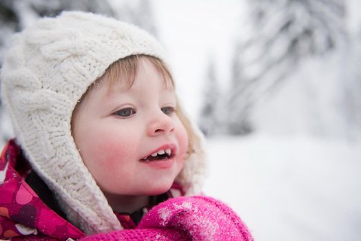 portrait of happy smiling little girl outdoors, having fun and playing on fresh snow on snowy  winter day