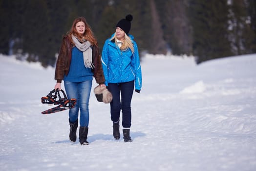 happy young  couple having fun and walking in snow shoes outdoor in nature at beautiful winter day. Health sport and relaxation