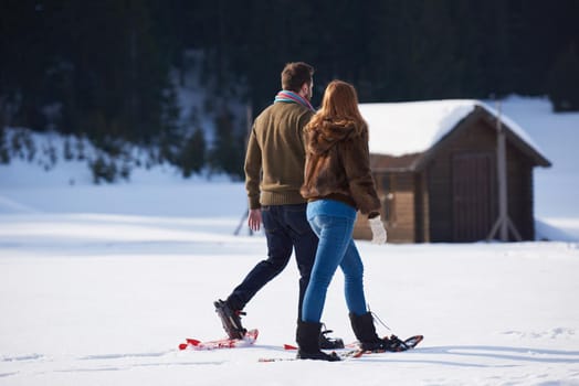 happy young  couple having fun and walking in snow shoes. Romantic winter relaxation scene