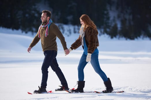 happy young  couple having fun and walking in snow shoes. Romantic winter relaxation scene