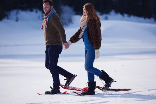 happy young  couple having fun and walking in snow shoes. Romantic winter relaxation scene