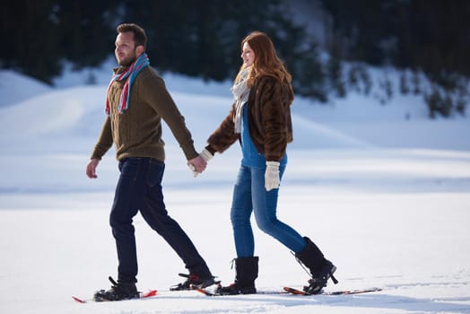 happy young  couple having fun and walking in snow shoes. Romantic winter relaxation scene