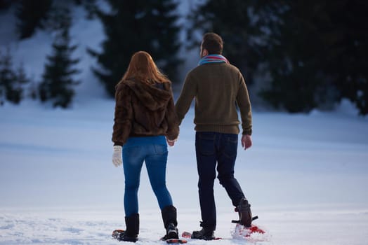 happy young  couple having fun and walking in snow shoes. Romantic winter relaxation scene