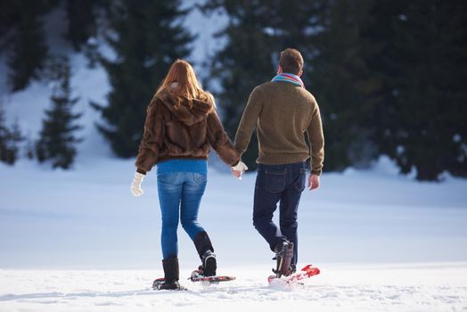 happy young  couple having fun and walking in snow shoes. Romantic winter relaxation scene