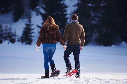 happy young  couple having fun and walking in snow shoes. Romantic winter relaxation scene