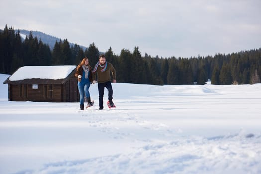 happy young  couple having fun and walking in snow shoes. Romantic winter relaxation scene