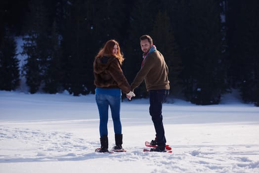 happy young  couple having fun and walking in snow shoes. Romantic winter relaxation scene