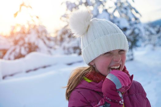 portrait of cute little girl  while eating icicle  on beautiful winter day with fresh snow