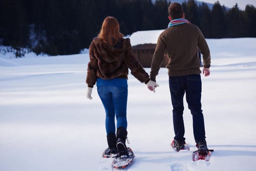 happy young  couple having fun and walking in snow shoes. Romantic winter relaxation scene