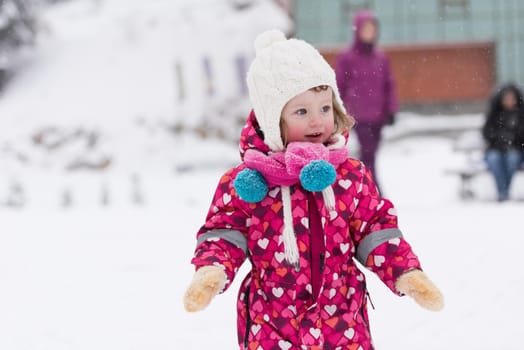 portrait of happy smiling little girl child outdoors having fun and playing on snowy winter day