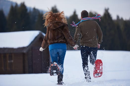 happy young  couple having fun and walking in snow shoes. Romantic winter relaxation scene