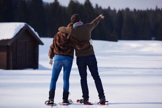 happy young  couple having fun and walking in snow shoes. Romantic winter relaxation scene