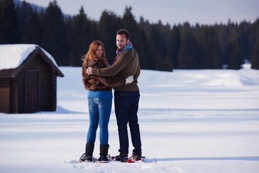 happy young  couple having fun and walking in snow shoes. Romantic winter relaxation scene