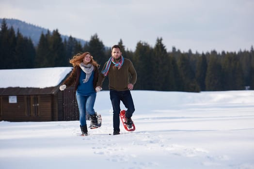 happy young  couple having fun and walking in snow shoes. Romantic winter relaxation scene