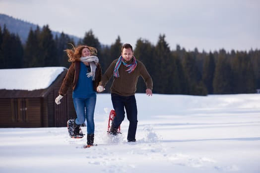 happy young  couple having fun and walking in snow shoes. Romantic winter relaxation scene