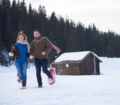 happy young  couple having fun and walking in snow shoes. Romantic winter relaxation scene