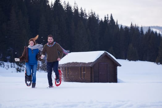 happy young  couple having fun and walking in snow shoes. Romantic winter relaxation scene