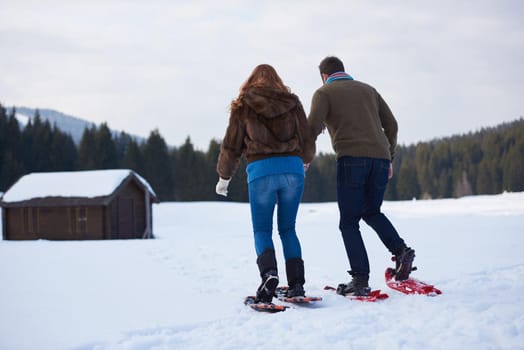 happy young  couple having fun and walking in snow shoes. Romantic winter relaxation scene