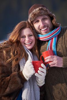 portrait of happy young couple outdoor on winter day drinking warm tea