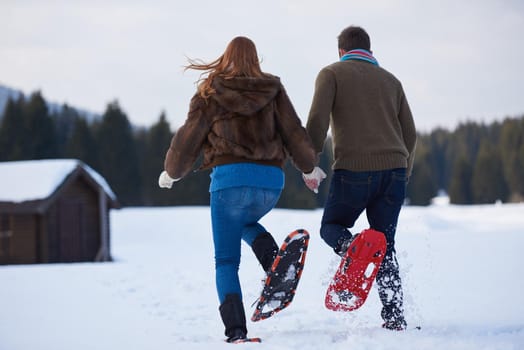 happy young  couple having fun and walking in snow shoes. Romantic winter relaxation scene