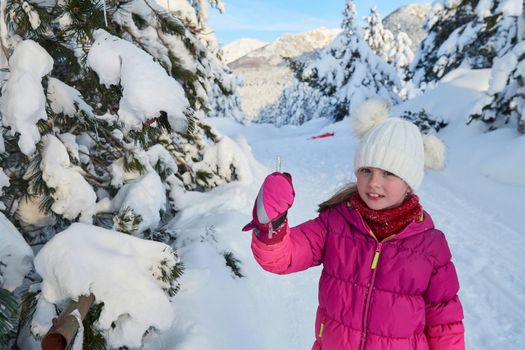 portrait of cute little girl  while eating icicle  on beautiful winter day with fresh snow