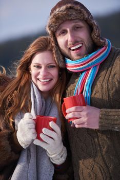 portrait of happy young couple outdoor on winter day drinking warm tea