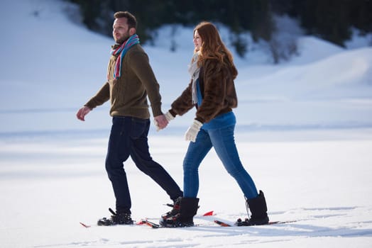 happy young  couple having fun and walking in snow shoes. Romantic winter relaxation scene