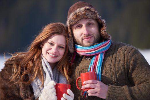 portrait of happy young couple outdoor on winter day drinking warm tea