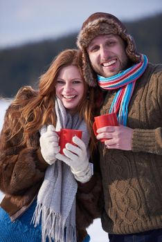 portrait of happy young couple outdoor on winter day drinking warm tea