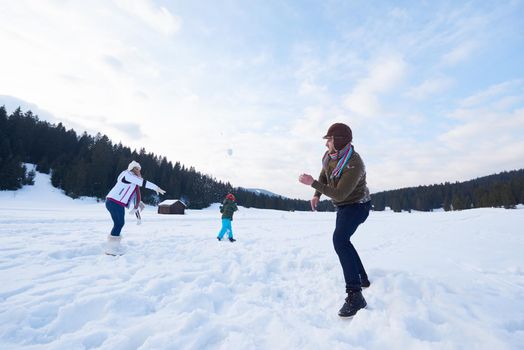 happy young  family playing in fresh snow  at beautiful sunny winter day outdoor in nature