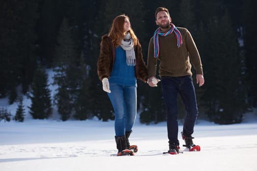 happy young  couple having fun and walking in snow shoes. Romantic winter relaxation scene